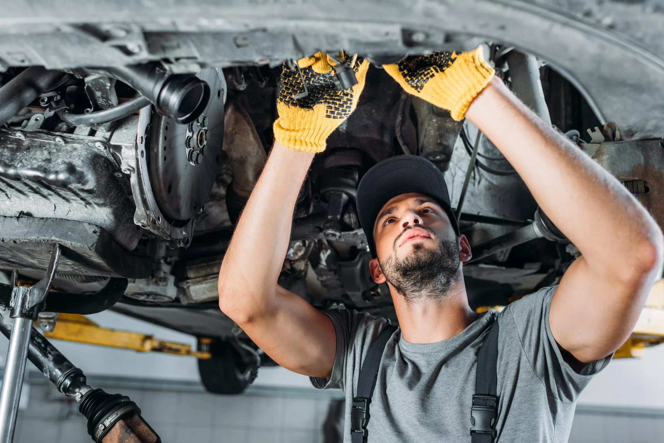 Technician inspecting the underside of a raised vehicle